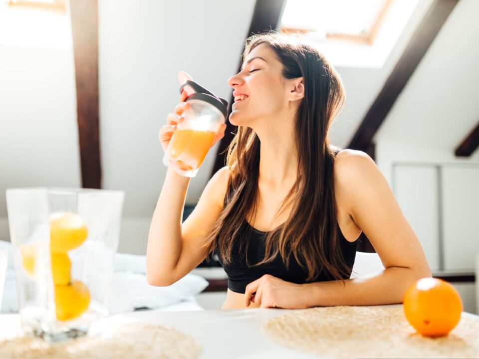 mulher feliz tomando suco de laranja vitamina c