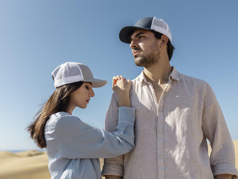 Homem e mulher no utilizando bonés no meio do deserto