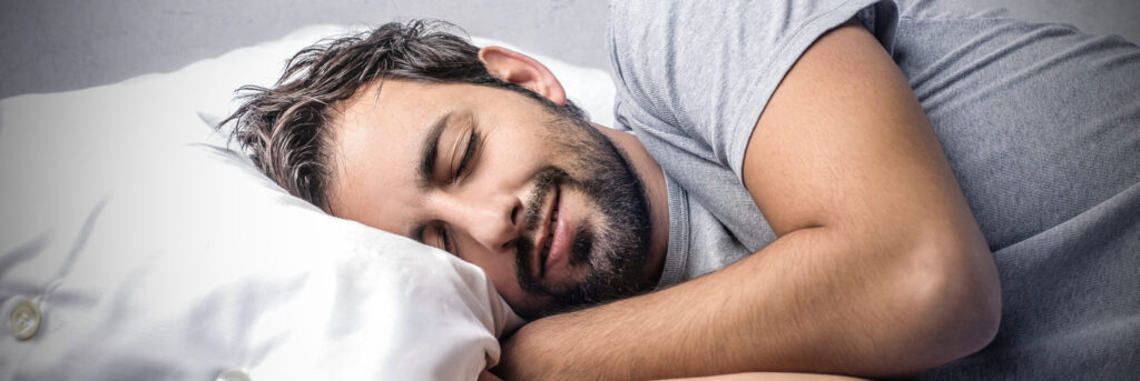 Homem deitado na cama, apoiado no travesseiro