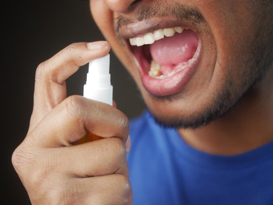 homem segurando um tadalafila em spray e apontando para sua boca