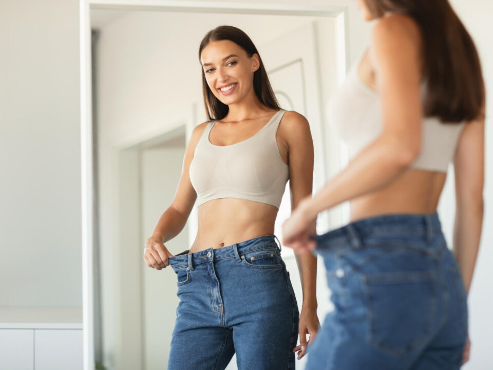 Moça se olhando no espelho e vendo o tanto que emagreceu.