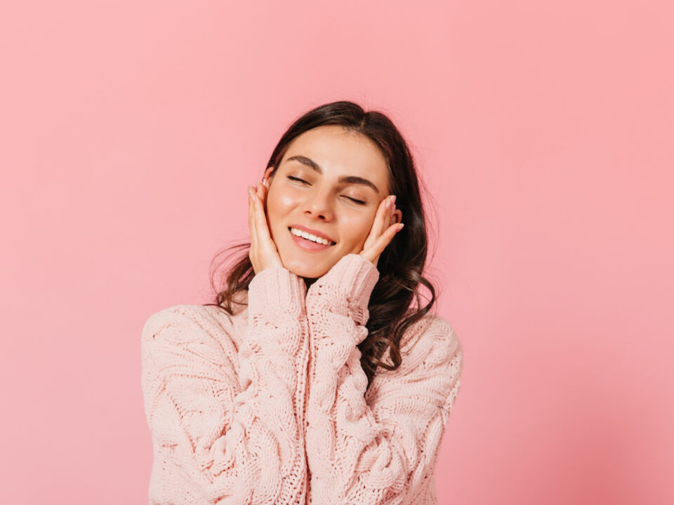 Moça bonita sorrindo, com as mãos no rosto