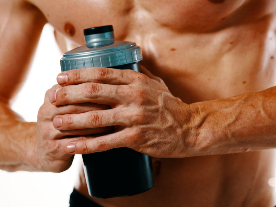 homem com perfil atlético segurando uma shakeira de creatina