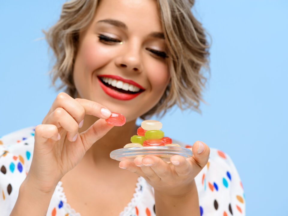 mulher loira de cabelos curtos, feliz segurando medicamento em gomas