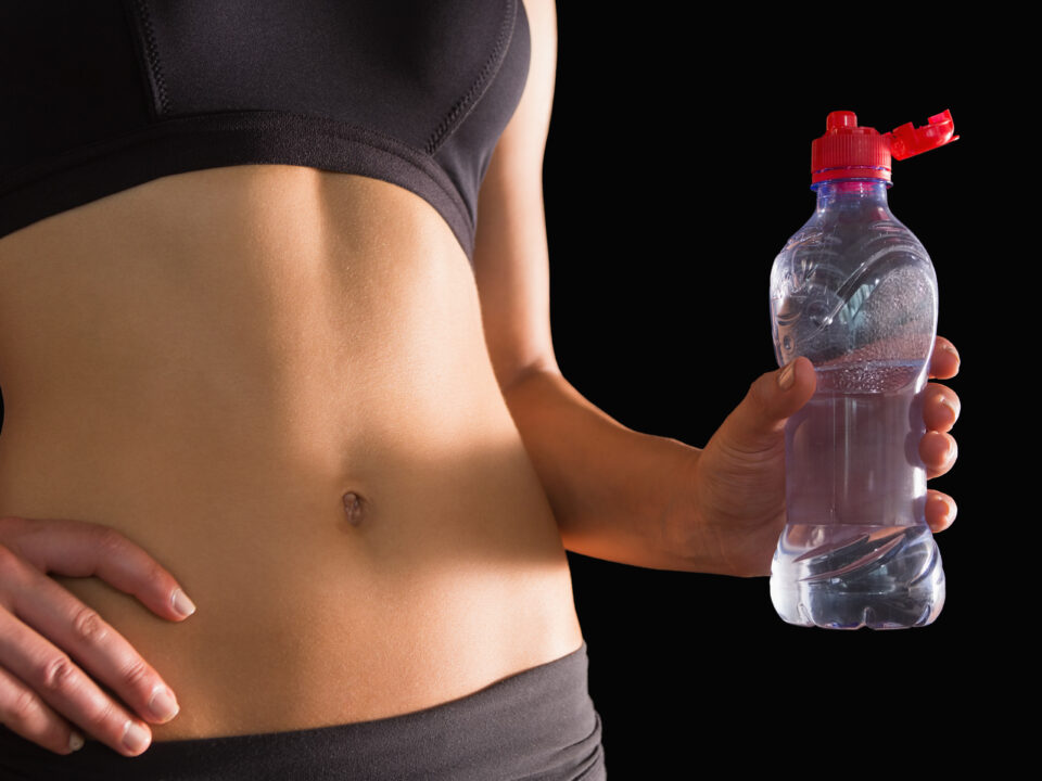 mulher magra com uma garrafa de agua na mão